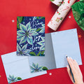 Load image into Gallery viewer, The inside of Tree-Free’s Sparkling Pointsettia card, with the cover and envelope in the background.
