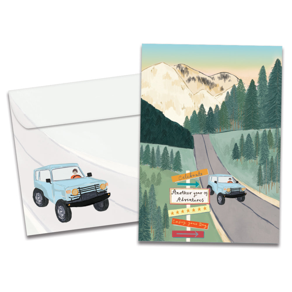 Cover of Year of Adventures Birthday card (featuring script text next to artwork of a car driving down a mountain road) and its matching envelope